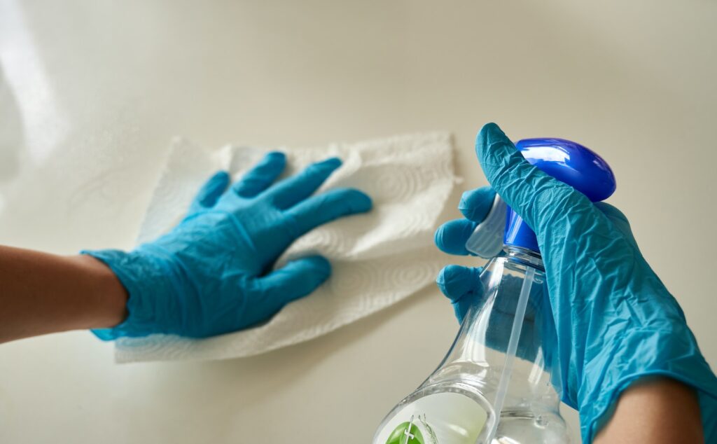 Person holding blue textile near clear glass bottle