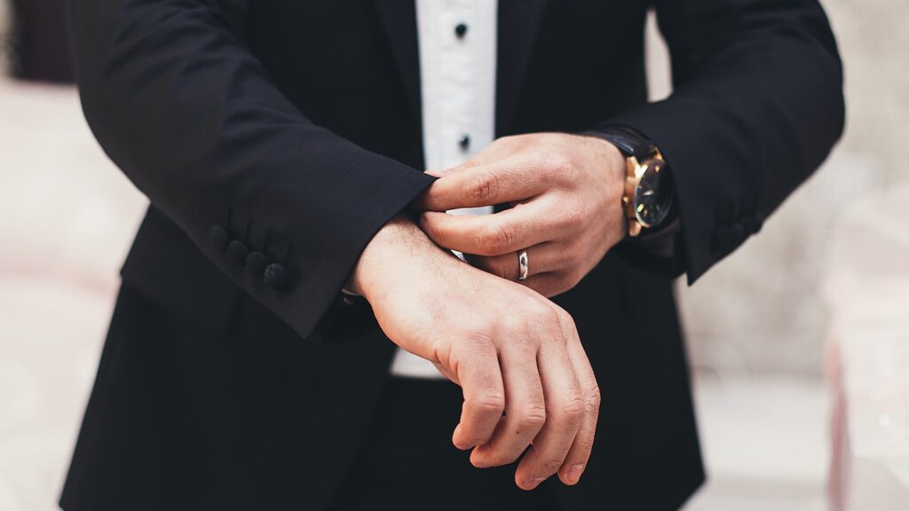 A man's hands adjusting the cuffs of his black suit