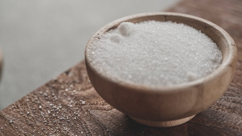 a wooden bowl filled with sugar on top of a wooden table