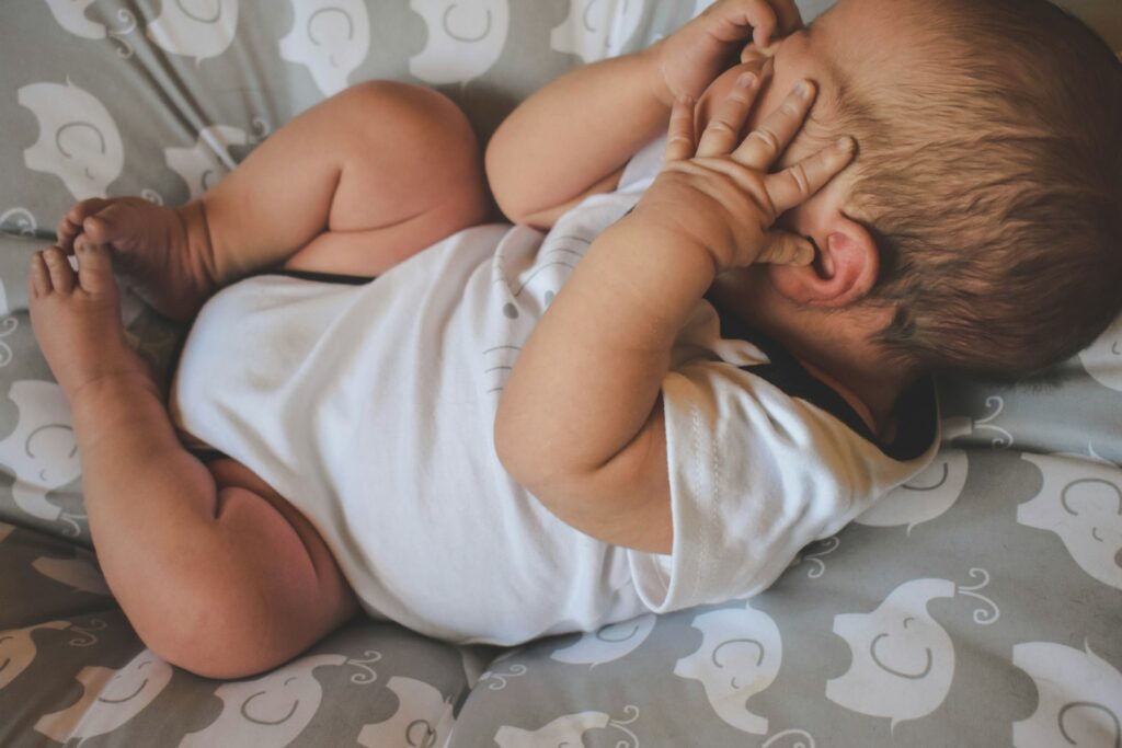 baby in white shirt lying on bed