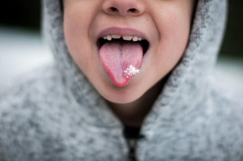 person in gray hoodie showing tongue