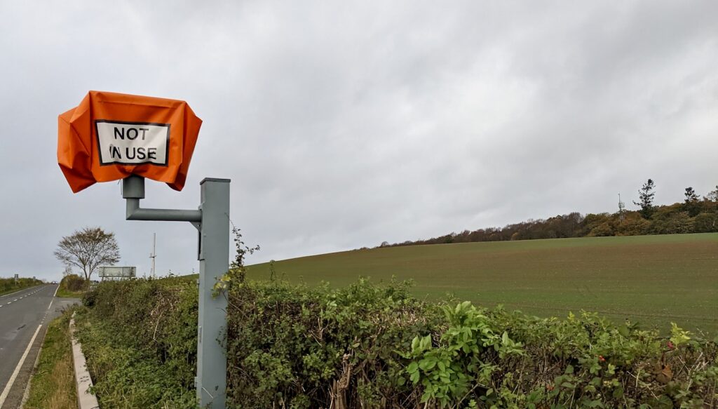 a sign on a pole next to a field of plants