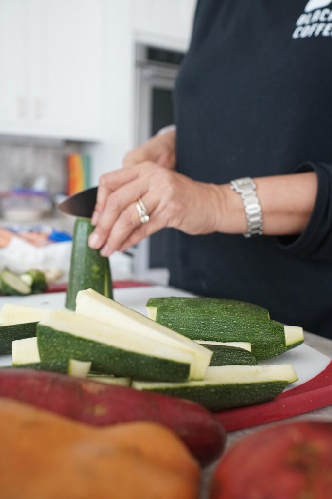 person holding sliced cucumber on brown wooden chopping board